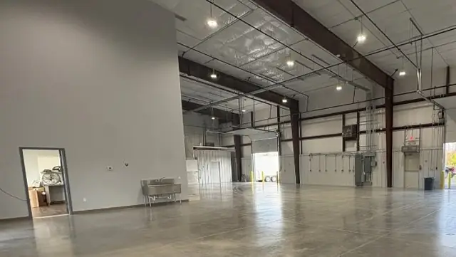 Finished clear-span warehouse interior with sealed concrete floor and high-bay lights at Twin City Produce